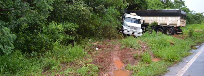 Após frear bruscamente em pista molhada, carreta faz “L” e colide contra barranco