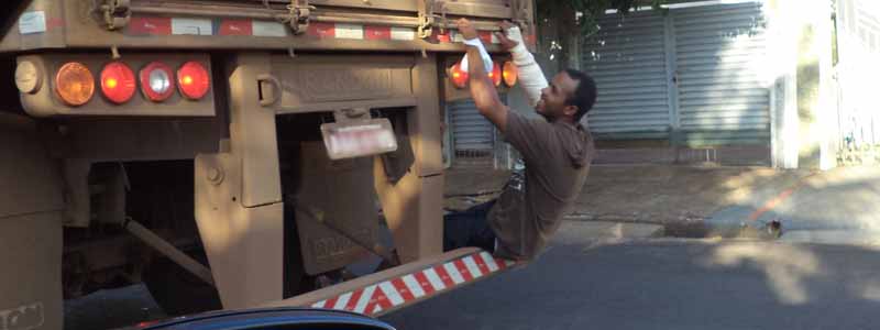 Homem com o braço engessado é flagrado sentado em para-choque de carreta em movimento