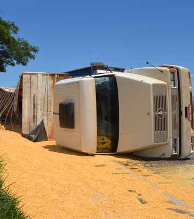 Carreta carregada de milho tomba ao tentar fazer trevo