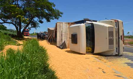 Carreta carregada de milho tomba ao tentar fazer trevo