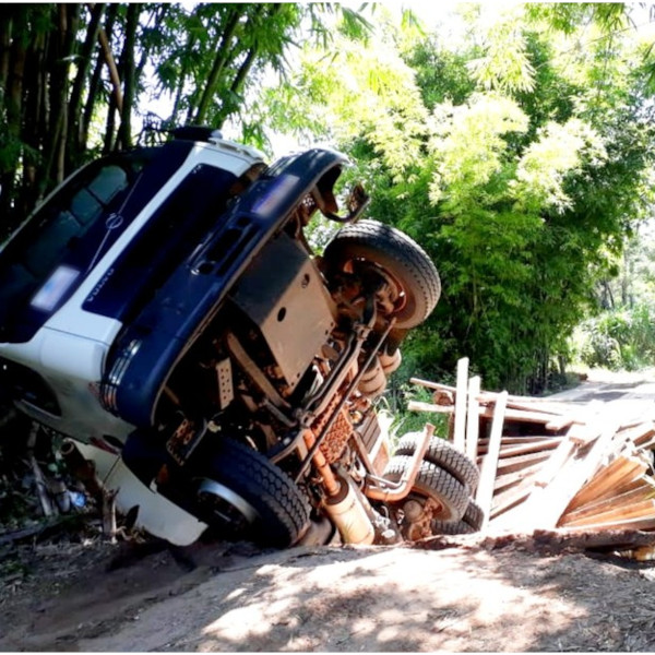 Caminhão carregado de cascalho cai ao atravessar em ponte de madeira 